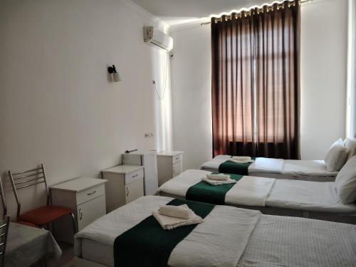 a room with three beds and a window at Chevrolet Hotel in Namangan