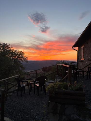a sunset with a table and chairs in front of a house at Agriturismo Colle Sereno in Castiglione dʼOrcia