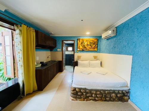 a bedroom with a bed and a blue wall at Nina's Aqua - Private Pool Villa & Plunge Pool Studios, Anjuna in Anjuna