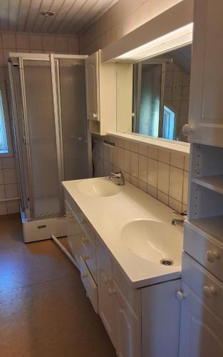 a white bathroom with a sink and a shower at Sundqvistens basement in Emkarby