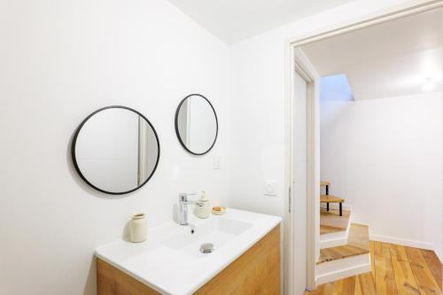 a bathroom with a sink and two mirrors on the wall at Maison de Charme - Écrin de Nature in Saint-Privat