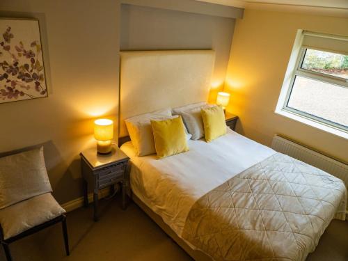 a bedroom with a bed with yellow pillows and a window at Bagshaw Lodge in Bakewell