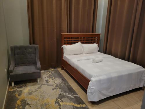 a bedroom with a bed and a chair in it at City Link Complex Ressort in Mwanza