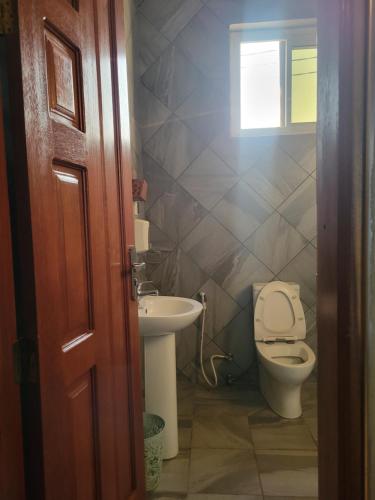 a bathroom with a toilet and a sink at City Link Complex Ressort in Mwanza