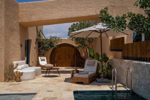 a patio with an umbrella and chairs and a pool at Oinopia Country Villas in Egina