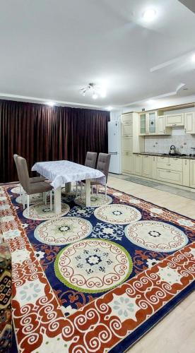 a dining room with a table and chairs on a rug at Яншина 6 in Qyzylorda