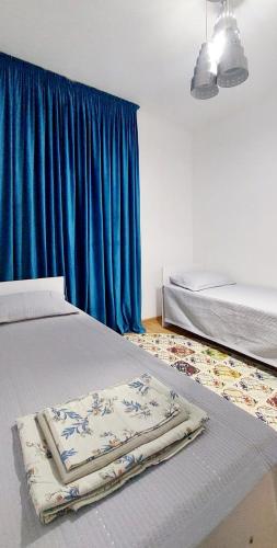 a bedroom with two beds and a blue curtain at Яншина 6 in Qyzylorda