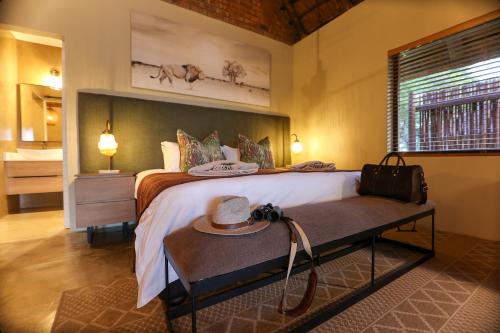 a bedroom with a bed and a table with a hat on it at Senalala Safari Lodge in Klaserie Private Nature Reserve