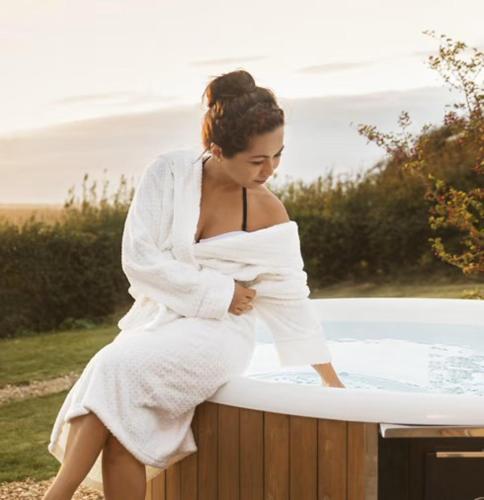 a woman in a white robe sitting in a bath tub at Landhaus Sweet Escape in Löningen