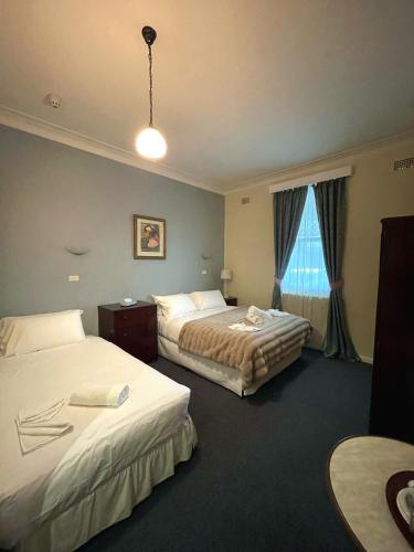 a hotel room with two beds and a window at The Old Vic Hotel in Canowindra