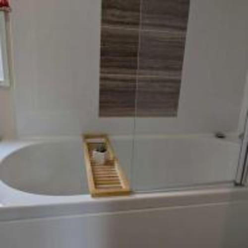 a bath tub with a shower with a wooden comb at 63 The Lea with decking Trevella Holiday Park in Crantock