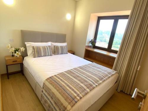 a bedroom with a large bed with a window at Casa Mamosteira Apartamento Refugio in Sandim