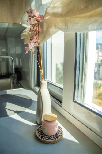a vase with flowers in it sitting next to a window at Saronic View Studio in Agioi Theodoroi