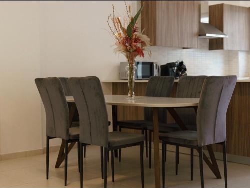 a dining room table with chairs and a vase of flowers at Halcyon Central Apartments in Larnaca