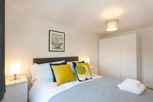 a bedroom with a bed with yellow and blue pillows at DBS Serviced Apartments - The Townhouse in Castle Donington