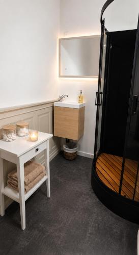 a bathroom with a sink and a shower and a table at Fontaine Studio Appartement in Ribérac