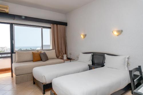 a hotel room with two beds and a couch at Studiotel Afoud in Agadir