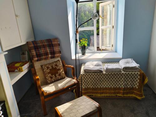 a room with a bed and a chair and a window at Tranquil Woodland Cottage by river Wye in Lydbrook