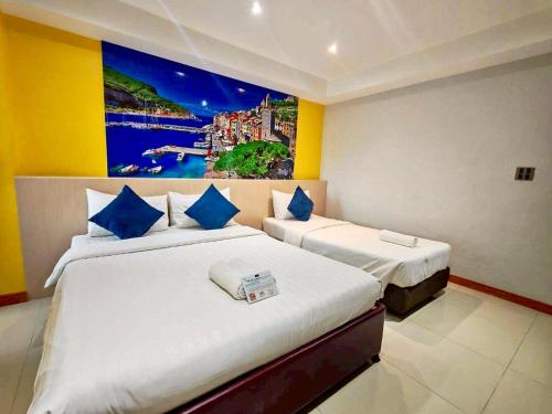 two beds in a room with a painting on the wall at Blue Orchids Hotel in Hat Yai