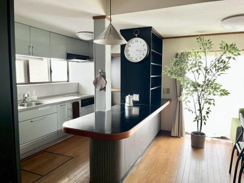 a kitchen with a counter with a clock on the wall at 民泊 Vacation rental "Tajimi-jyuku Kitaya" Base for trips to Ghibli Park,Tsumago-juku,Magome-juku in Tajimi