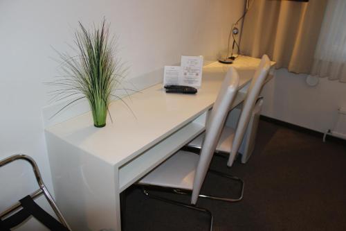 a white table with two chairs and a plant on it at Hotel Michael in Gerasdorf bei Wien
