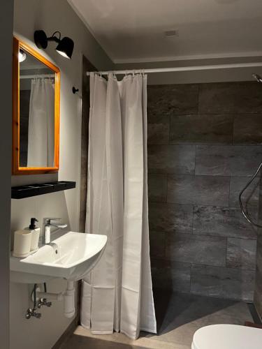 a bathroom with a white shower curtain and a sink at Boutique Hotel Roja in Roja