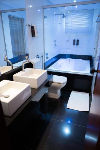 a bathroom with a sink and a tub and a toilet at Hz Hotel in Patos de Minas