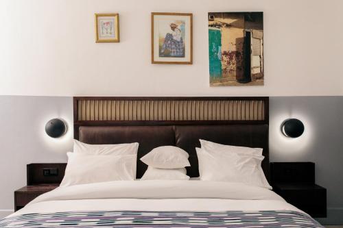 a bedroom with a large bed with white pillows at Hotel Lepic in Abidjan