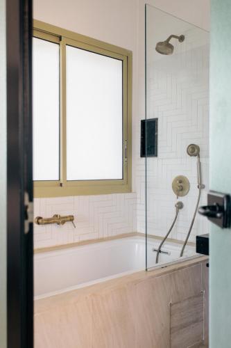 a bath tub in a bathroom with a window at Hotel Lepic in Abidjan