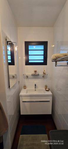 a white bathroom with a sink and a window at Superbe Suite parentale Chez l'habitant avec SPA et petit déjeuner in Saint-Pierre