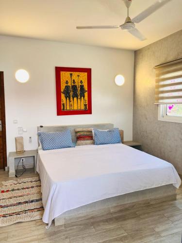ein Schlafzimmer mit einem großen weißen Bett und blauen Kissen in der Unterkunft Hôtel Mango GI in Saly Portudal