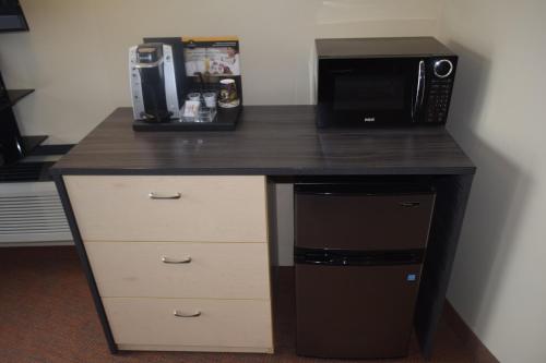 a desk with a microwave and a coffee maker at Motel Falcon in Brossard