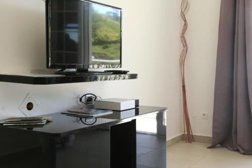 a living room with a television on a table at L'Eden des Colibris in Vieux-Habitants