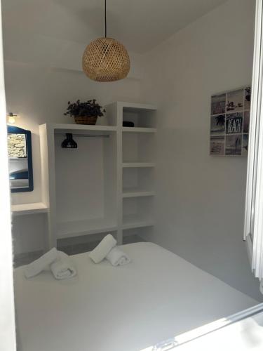 a white room with a bed and a potted plant at Meltemi Tinos in Agios Romanos