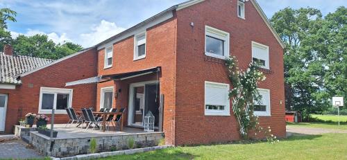 a red brick house with chairs and a patio at Ferienhaus Dat Landhuus 95158 in Rhauderfehn