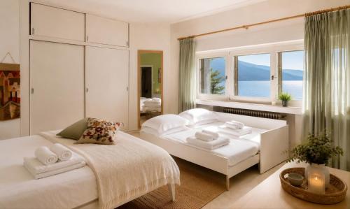 a white bedroom with a bed and a window at Villa Coccodrilla in Toscolano Maderno