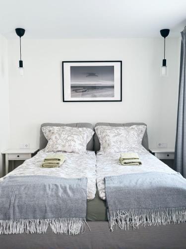a bed with two pillows and a picture on the wall at Liedagas in Kolka