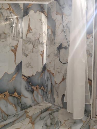 a bathroom with a shower with a marble wall at Casa Theopa in Corbu