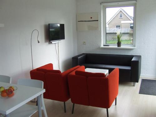 a living room with two red chairs and a couch at De Viool in Buren