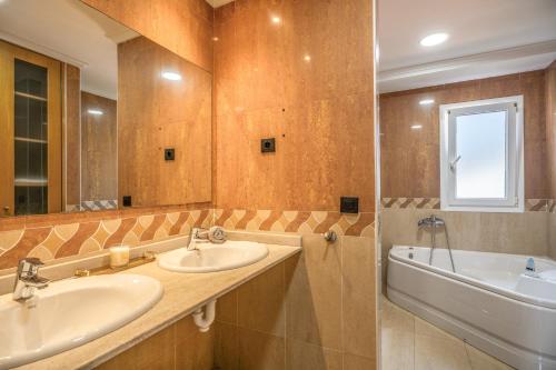 a bathroom with two sinks and a tub and a mirror at Villa Romeo in Oviedo