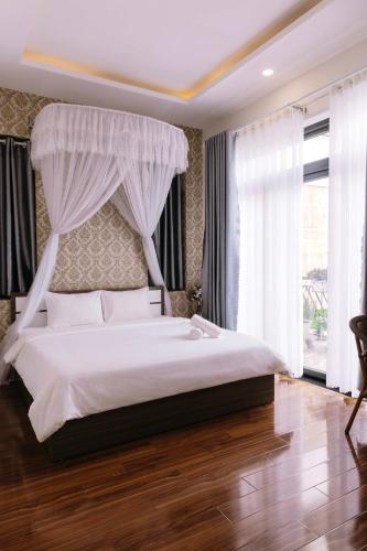 a bedroom with a large white bed with curtains at Hoanglee Villa in Da Thanh