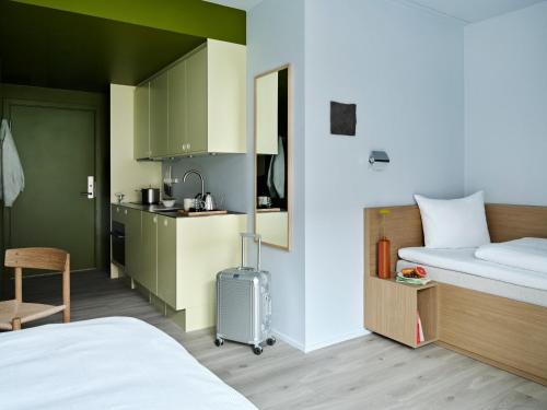 a small room with a bed and a kitchen at Folk Copenhagen in Copenhagen