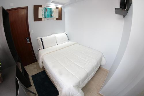a bed with white sheets and pillows in a room at Santo Antônio Hotel Ltda in Angatuba