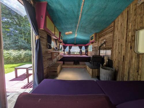 an inside view of a bus with a purple canopy at Budget stay, in lovely private setting with rustic charm, log burner, fire pit, campers kitchen & Eco Loo NO BEDDING SUPPLIED in Narberth