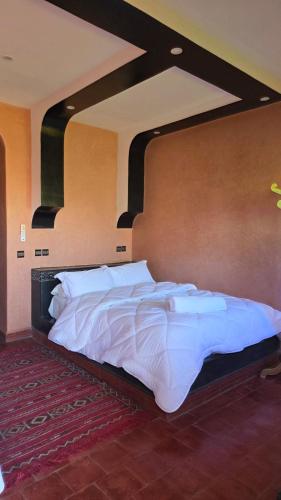 a bedroom with a large bed with white sheets at HOTEL RESTAURANT LA KaSBAH in Tinerhir