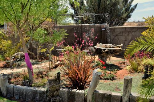 a garden with a fence and flowers in a yard at Art Guest House in Lutzville