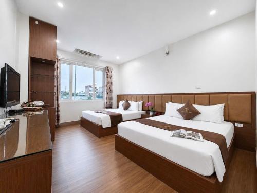 a hotel room with two beds and a television at Hồ Sen Xanh Hotel Hà Nội in Hanoi