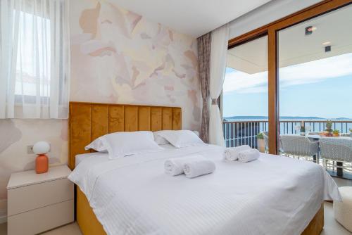 a bedroom with a white bed with towels on it at Royal Oak beachfront residence Trogir Seget Vranjica in Seget Vranjica