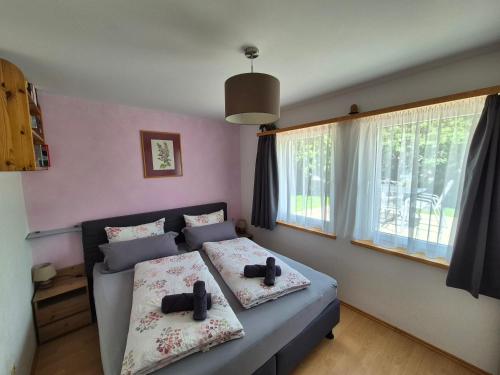 a bedroom with two beds and two windows at FeWo Aquileia Scuol, Gratisparken, Terrasse, Wifi, flexible Zimmerwahl, Familien in Scuol