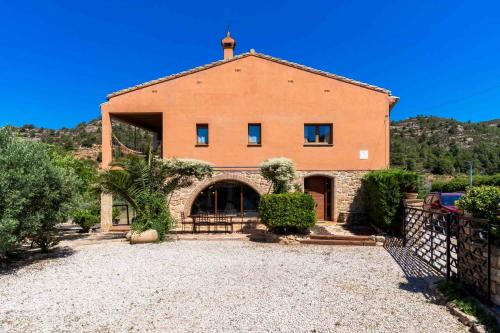 a large brick building with a fence in front of it at Casa rural en Terra Alta con vistas al Tossal d'Engrilló, cerca de la Vía Verde, espacios exteriores, doble barbacoa, ideal para familias, grupos y mascotas in Prat de Compte
